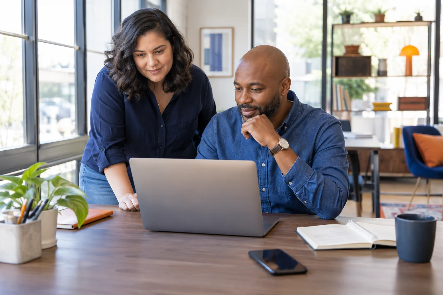Two colleagues working together at a laptop in a bright office